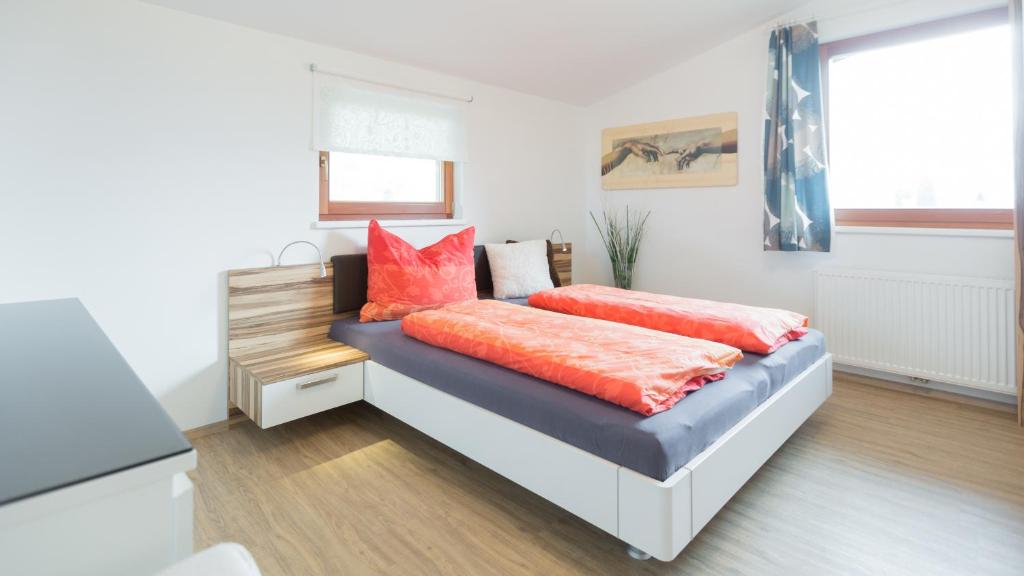 1 dormitorio con 1 cama con almohadas de color naranja en Merlin, en Lienz