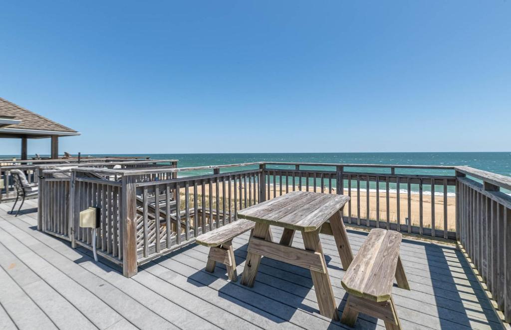 a wooden bench sitting on a boardwalk near the ocean at Ocean Song - 2 Bedroom Oceanfront Penthouse Condo in Kill Devil Hills, Spacious Layout in Kill Devil Hills