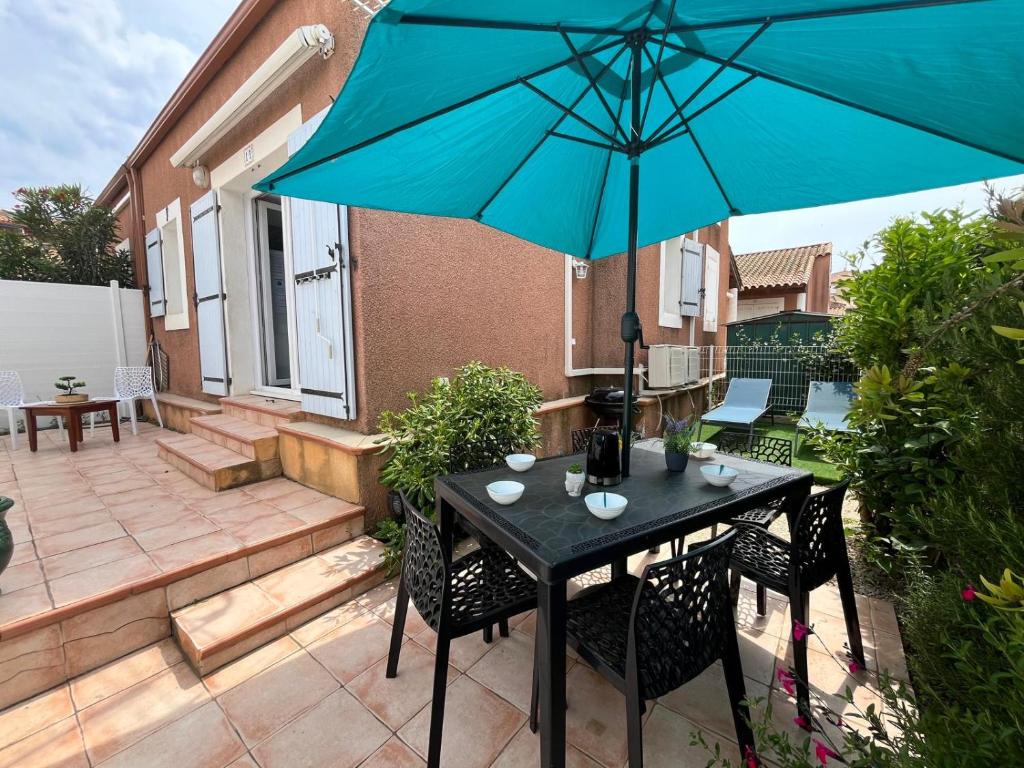 une terrasse avec une table et un parasol bleu dans l'établissement Serr, à Valras-Plage