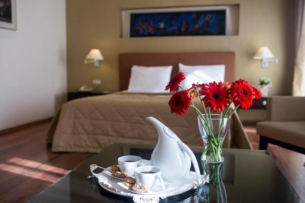 a room with a bed and a table with a vase with flowers at Davitel - Tobacco Hotel in Thessaloniki