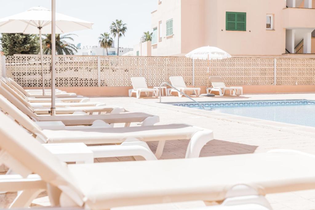a row of white lounge chairs next to a swimming pool at Hotel Golf Beach in Santa Ponsa