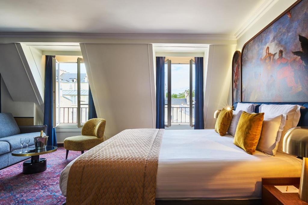 a hotel room with a large bed and a chair at H&ocirc;tel Le Versailles in Versailles