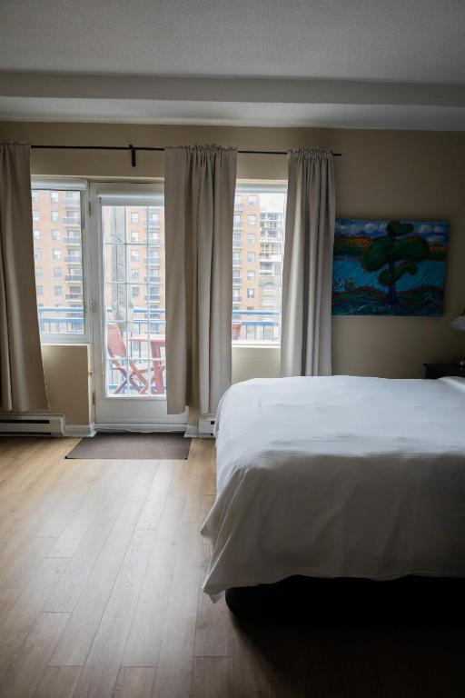 a bedroom with a bed and two large windows at ByWard Blue Inn in Ottawa