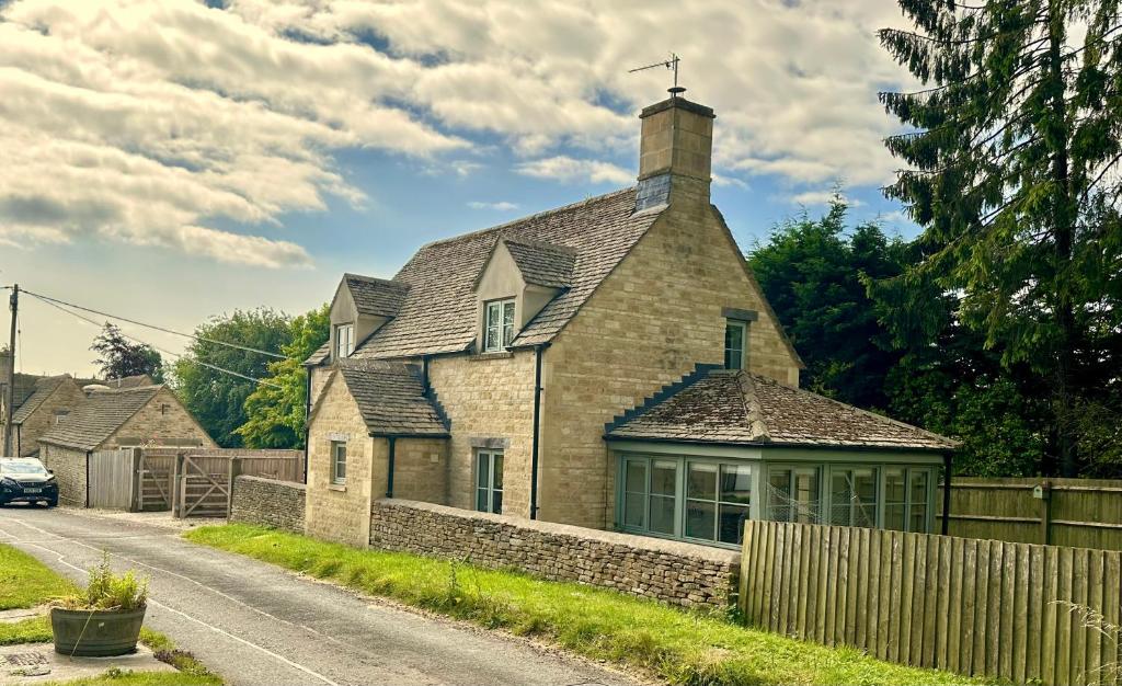 een oud bakstenen huis aan de kant van een weg bij Holly Cottage in Cirencester