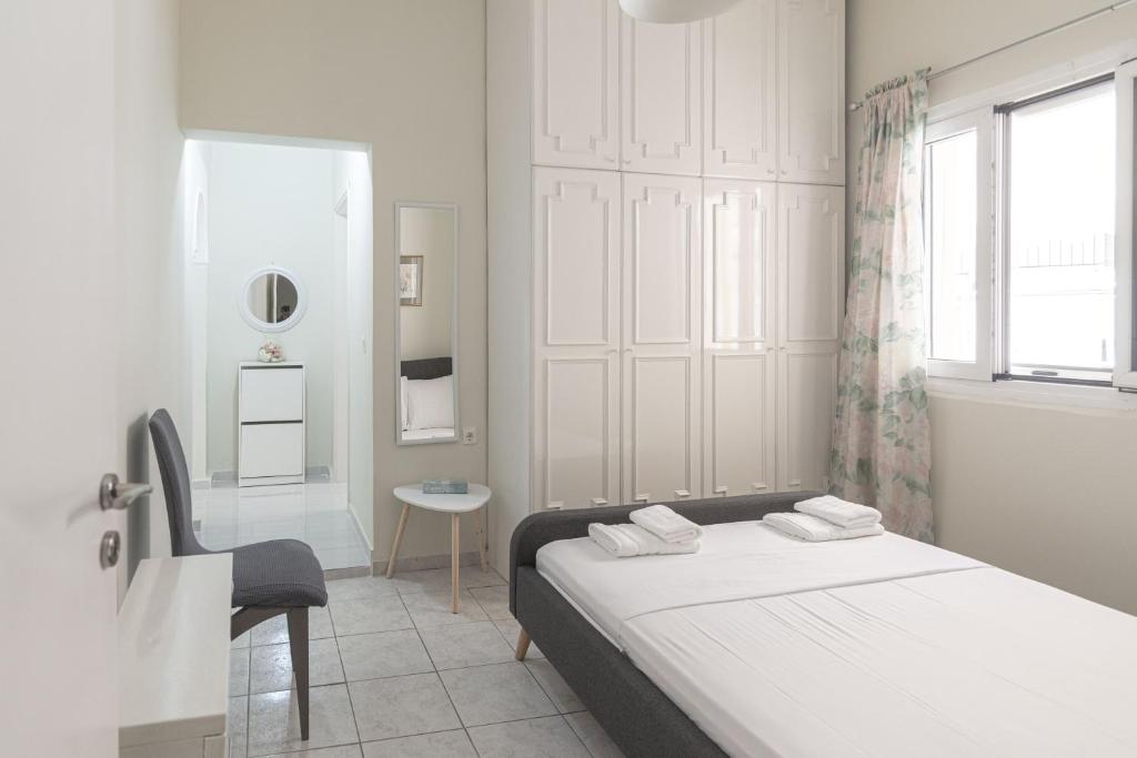a white bedroom with a bed and a chair at Portside Retreat by Efi 's in Ágios Rókkos