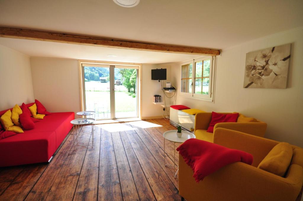 a living room with red and yellow couches and wooden floors at Waterfall Chalet in Stechelberg