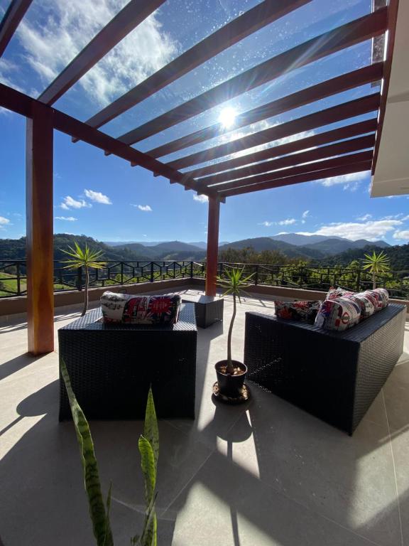 un patio con sofás y vistas a las montañas en Colina do Cristal, en Santo Antônio do Pinhal