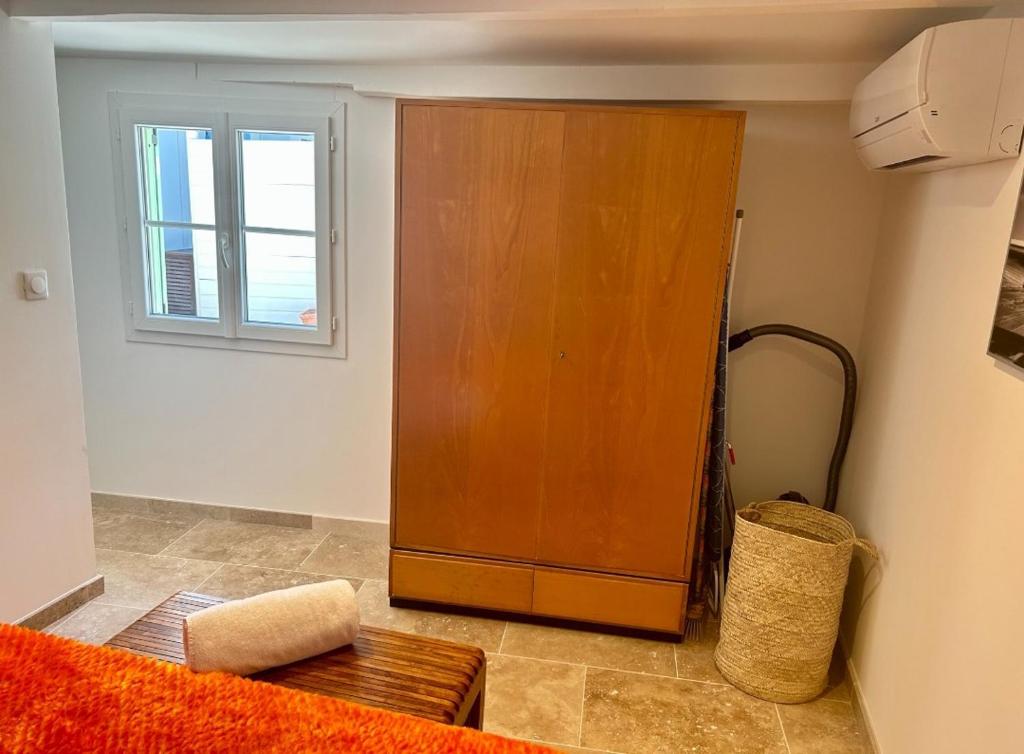Cette chambre comprend une grande armoire en bois et une fenêtre. dans l'établissement Charmant appartement près de la place des Lices, à Saint-Tropez