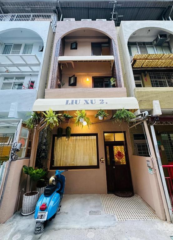 un edificio con uno scooter blu parcheggiato fuori di Liu Xu Homestay ll a Tainan