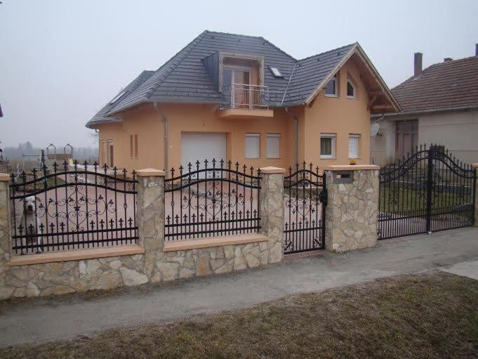 uma cerca em frente a uma casa com um portão em Termálvölgy Vendégház em Gelse