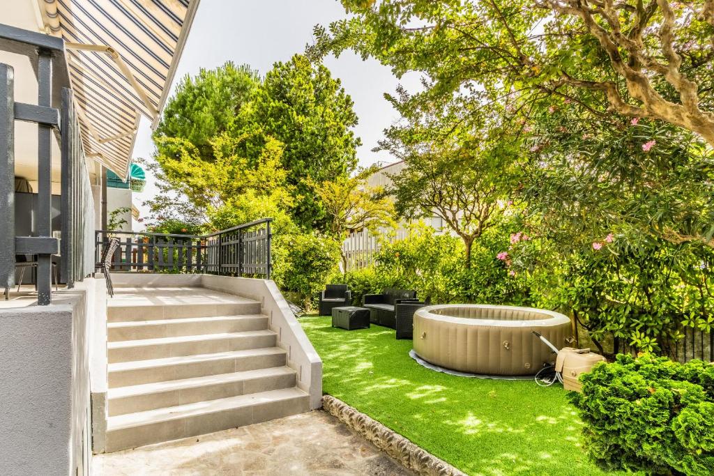 a backyard with a garden with green grass and stairs at GRADO HOUSE-Garden & Hydromassage-Sea-Free Parking in Grado