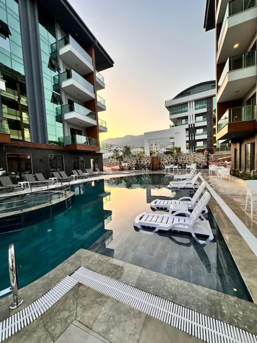 a swimming pool with white lounge chairs in a building at Silence garden suite iki yatak odalı daire in Alanya