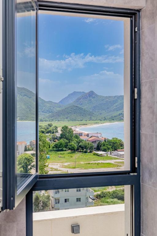 a window with a view of the water and mountains at Hotel AQUILO in Petrovac na Moru