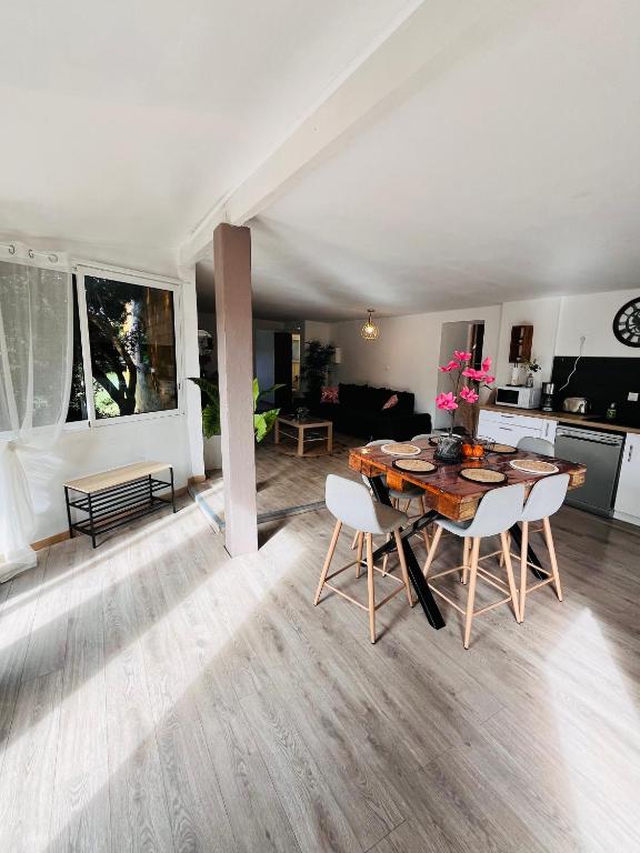 une cuisine et une salle à manger avec une table et des chaises en bois dans l'établissement Location T3 jardin avec piscine, à Mèze