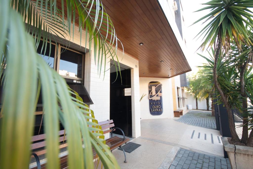 a building with a porch with palm trees in front of it at Hotel Ouro Lavras in Lavras