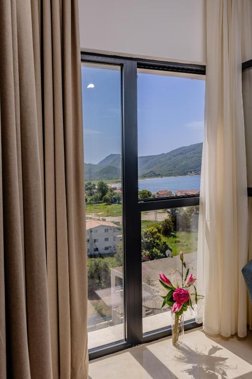 a room with a large window with a vase of flowers at Hotel AQUILO in Petrovac na Moru