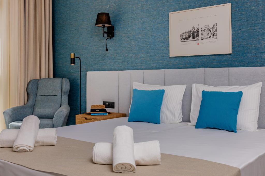 a bedroom with a large bed and a blue wall at Hotel AQUILO in Petrovac na Moru