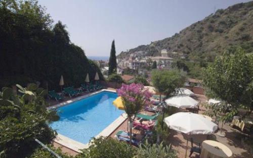 una piscina con ombrelloni e sedie accanto a una montagna di Hotel Villa Sirina a Taormina