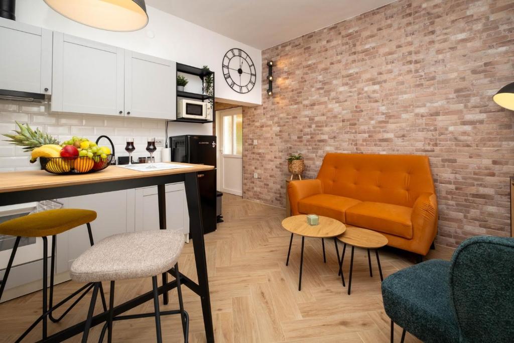 a living room with an orange couch and a kitchen at Relaxing Holiday Apartment in Kornić