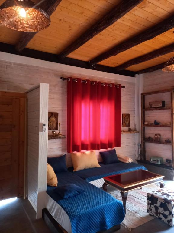 a living room with a blue couch and a red curtain at Rahoni Park & Suites in Dhërmi
