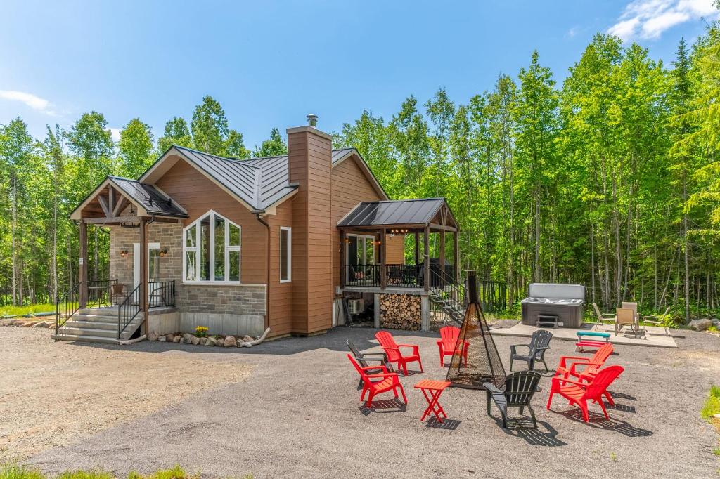 Una casa con sillas rojas y una parrilla. en Natur Rustik - En pleine nature avec Spa, en Petite-Rivière-Saint-François