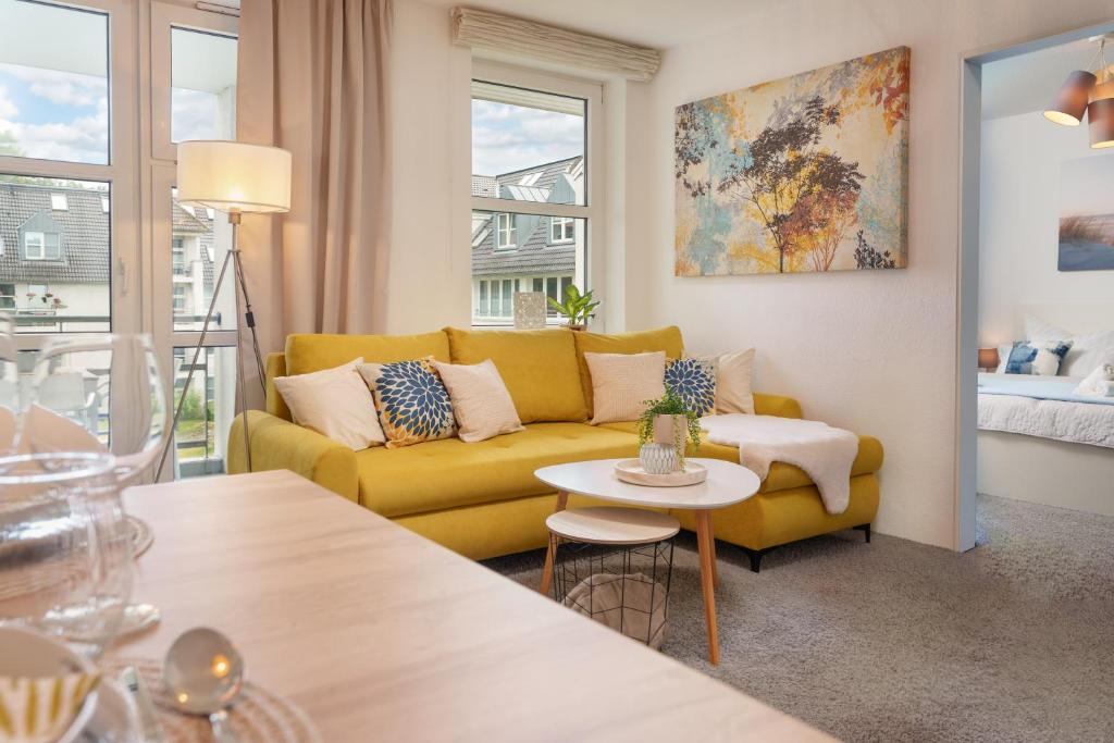 a living room with a yellow couch and a table at Apartment Meerblick-Balkon-Strand-Golf-TV-Stilvoll in Eckernförde