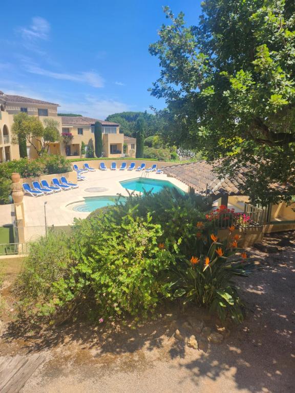 une piscine avec des chaises bleues et des fleurs dans une cour dans l'établissement Grand logement tout confort pour 4 personnes dans une résidence de haut standing, à Saint-Tropez