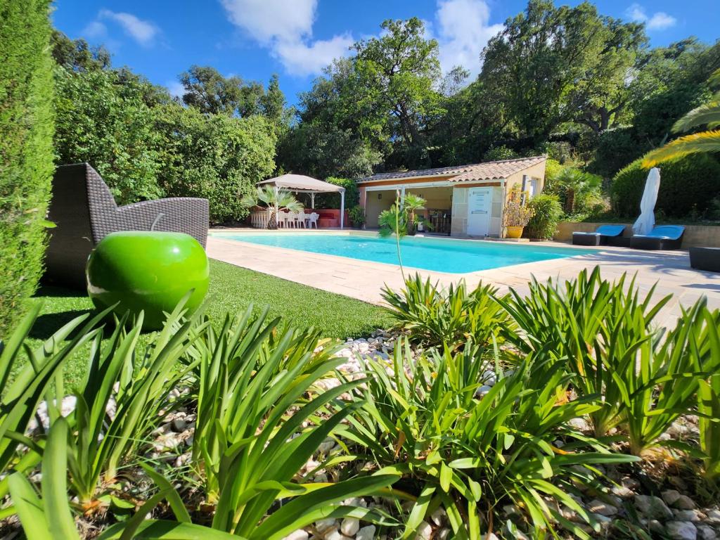 un jardin avec une piscine et une maison dans l'établissement Demeure raffinée et exceptionnelle dans un cadre de vacances idéal à l'ombre des pins parasols, au Plan-de-la-Tour