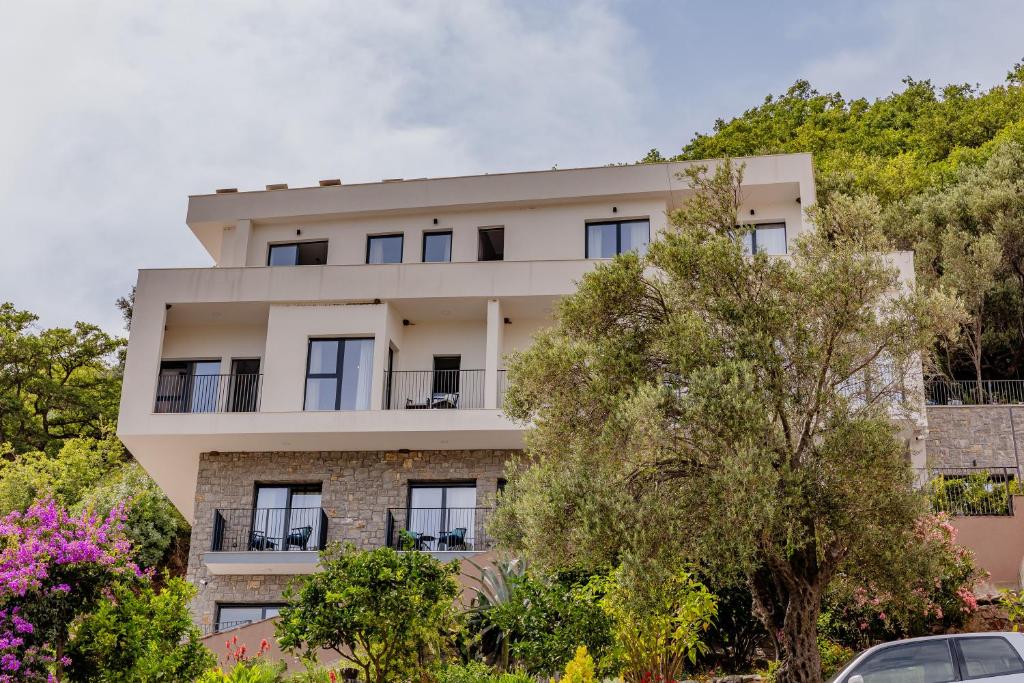 an apartment building with trees in front of it at Hotel AQUILO in Petrovac na Moru
