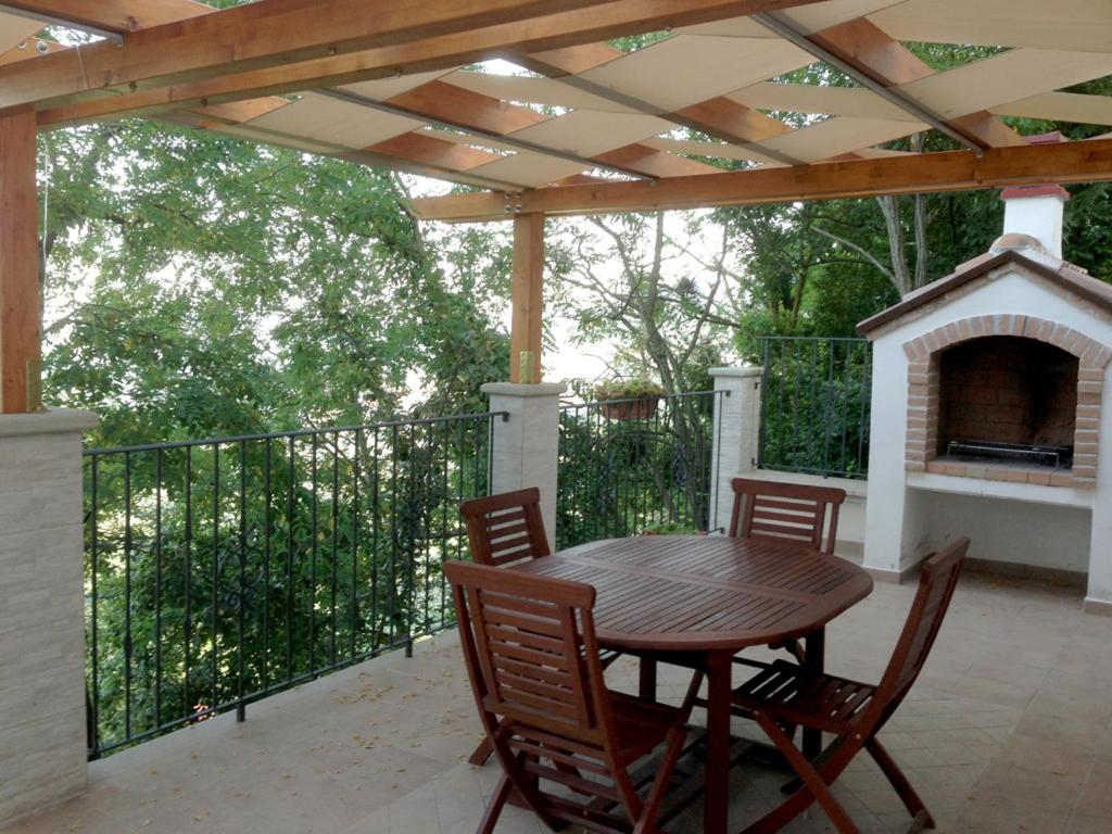 une table et des chaises en bois sur une terrasse avec une cheminée dans l'établissement Il Baglivo, à Agnone