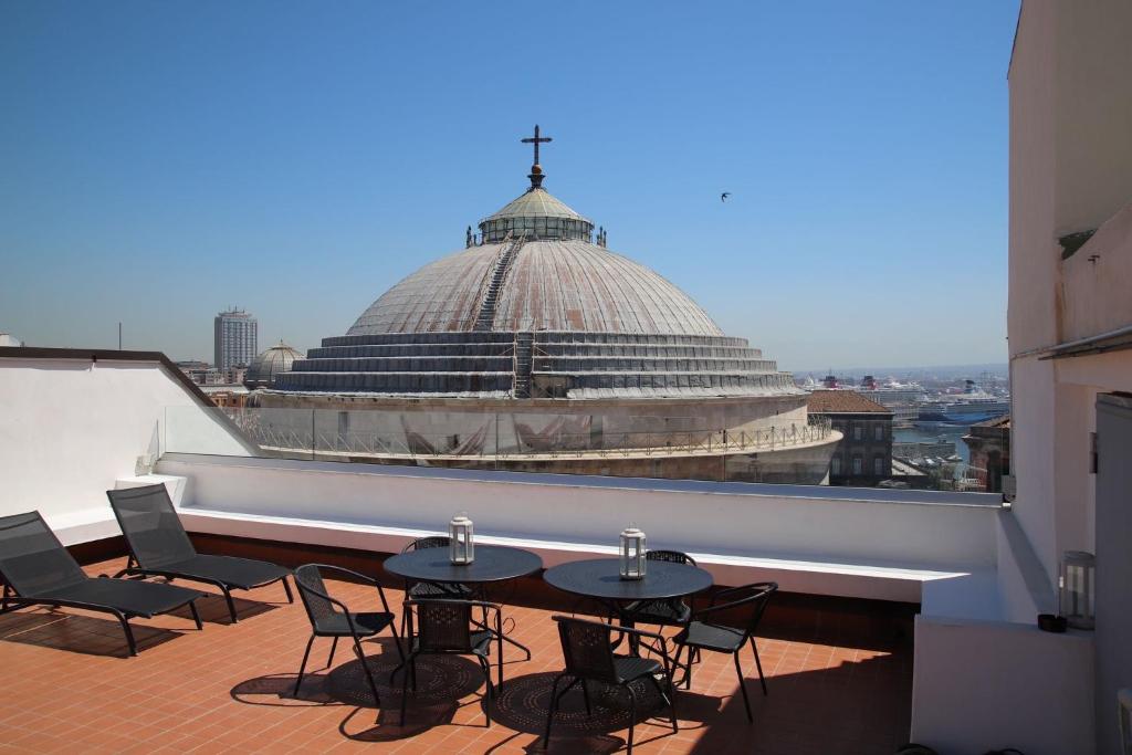 a balcony with tables and chairs and a building at Lucullo's Rooftop in Naples