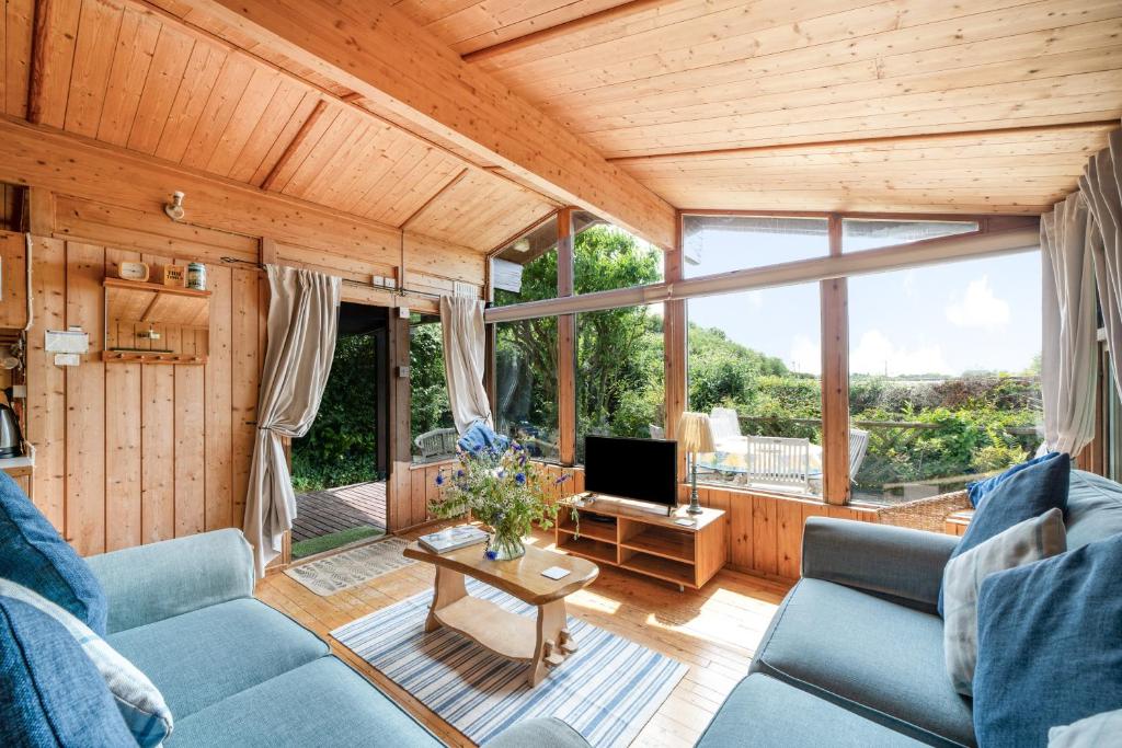 un salon avec un canapé bleu et une télévision dans l'établissement Scandinavian Style Lodge in Rock, à Wadebridge