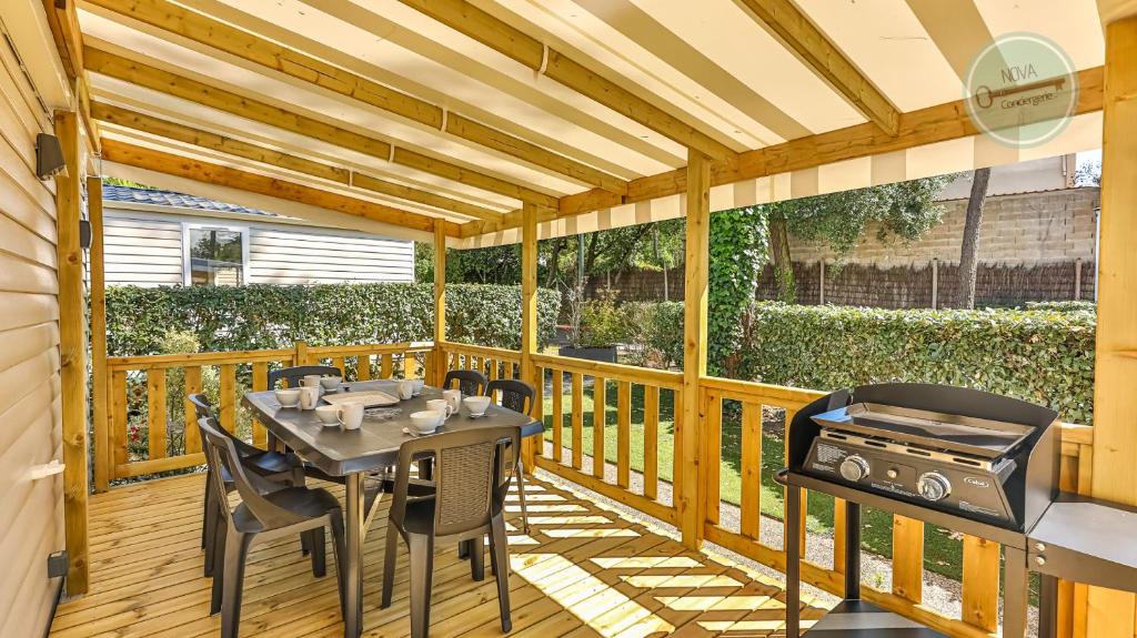 une terrasse en bois avec une table et un grill dans l'établissement Le Bois Dormant 761 by NOVA, à Saint-Jean-de-Monts
