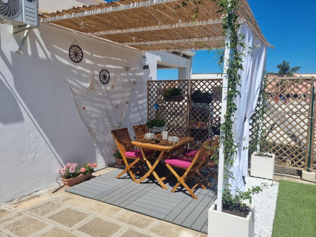 un patio con una mesa de madera y sillas bajo una pérgola en La terrazza di Zoe - Castromediano ( Lecce), en Cavallino di Lecce