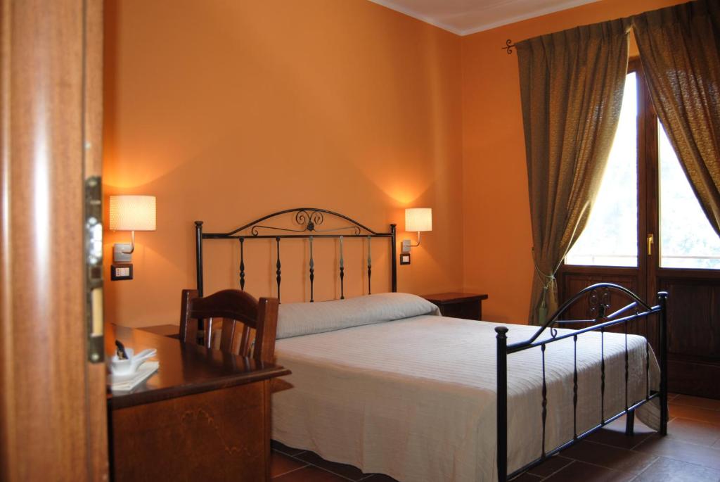 a bedroom with a bed and a desk and a window at Al Giumani in Mammola