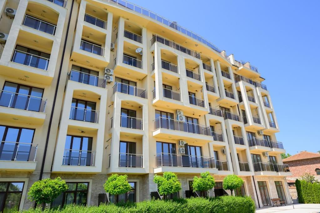 a yellow building with trees in front of it at Azur Properties ap19 in Shkorpilovtsi