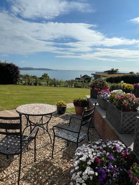 a patio with a table and chairs and flowers at The Stoep in Paignton