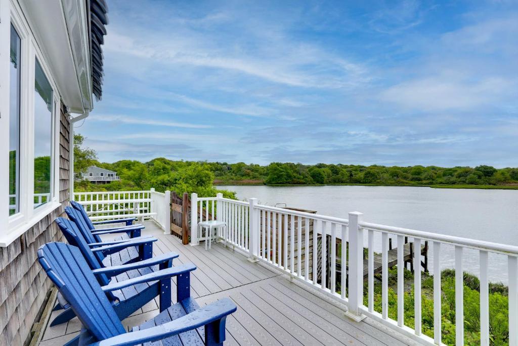 two blue chairs sitting on a porch overlooking a lake at Cozy Narragansett Cottage with Dock and Outdoor Shower in Narragansett