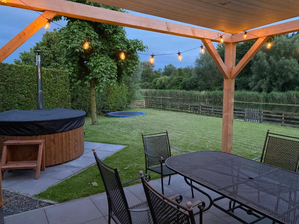un patio avec une table, des chaises et un barbecue dans l'établissement Villa Riverside met hottub, eigen aanlegsteiger, zwemtrap, trampoline en kano's, à Zeewolde