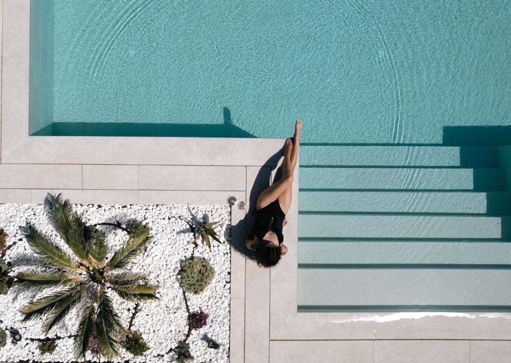 a woman doing a yoga pose by a swimming pool at Sivota Hotel in Sivota
