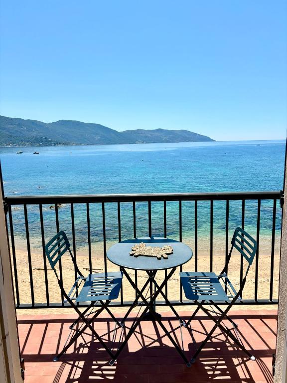 une table et des chaises sur un balcon donnant sur l'océan dans l'établissement A 20min d AJACCIO, Grand studio 3 personnes - pieds dans l'eau - accès direct plage - vue mer exceptionnelle, à Casaglione
