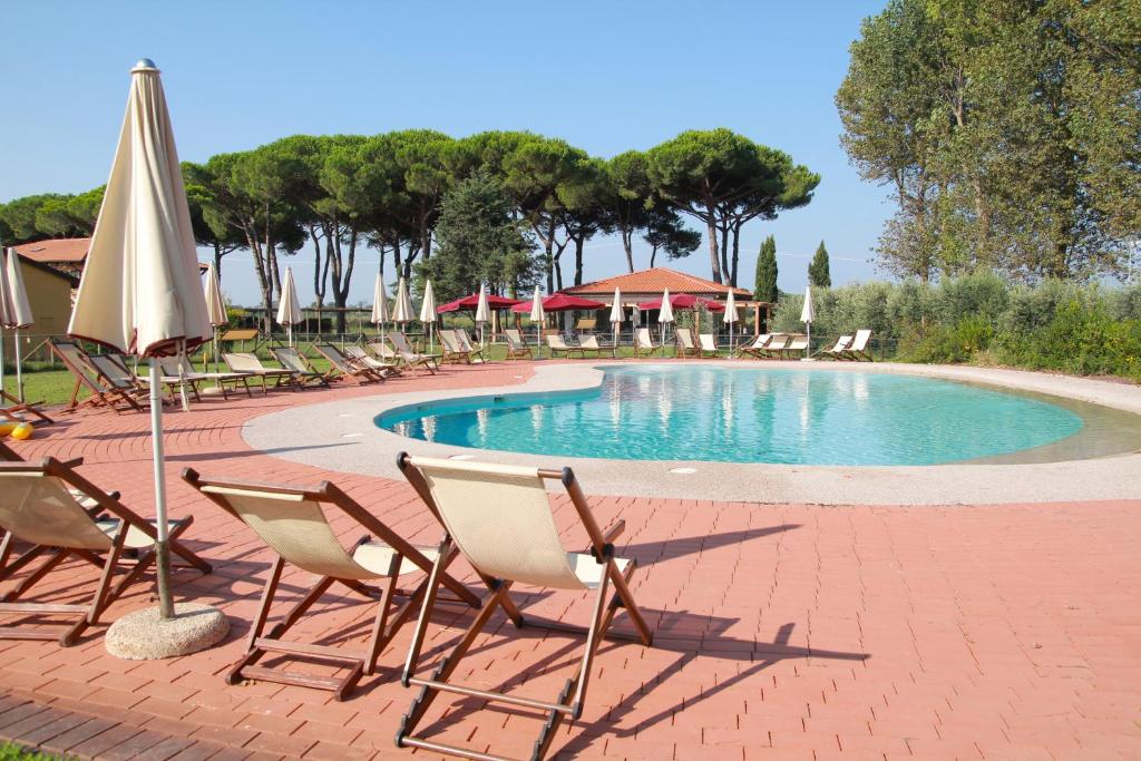 a group of chairs and a swimming pool with an umbrella at La Fattoria di Tirrenia in Tirrenia