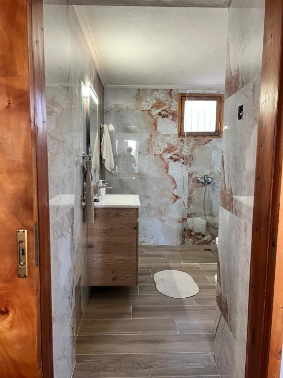 a bathroom with a shower and a sink and a mirror at Village House in Petaloú