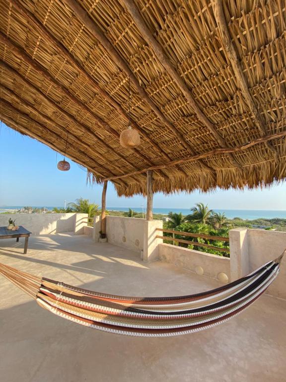 a hammock under a straw umbrella on the beach at La Casa del Sol Beachfront in El Cuyo