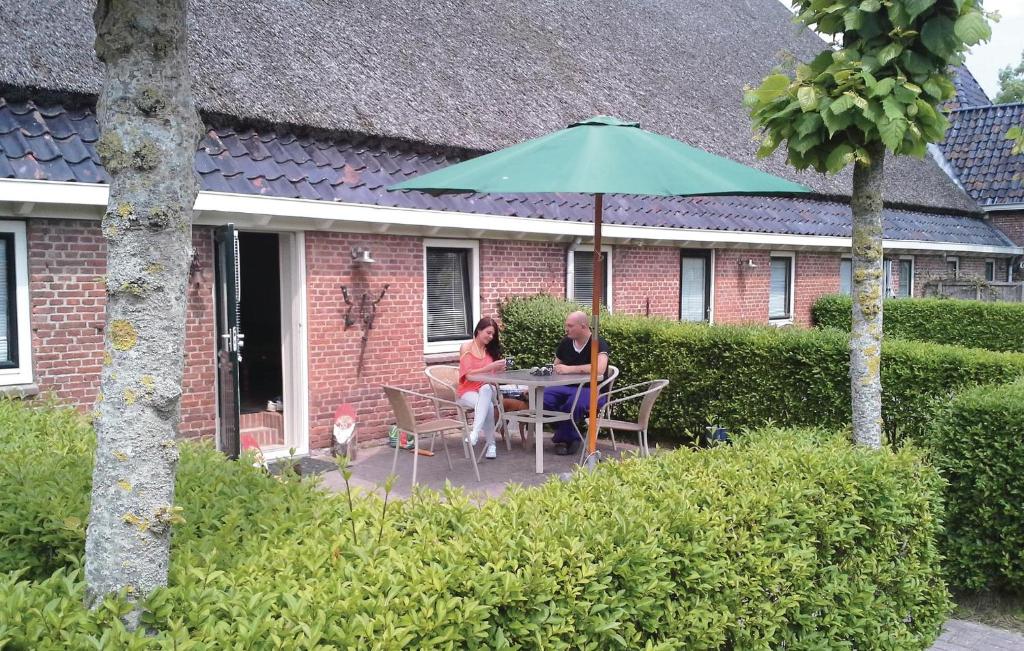 two people sitting at a table under an umbrella at Pet Friendly Apartment In Paesens in Paesens