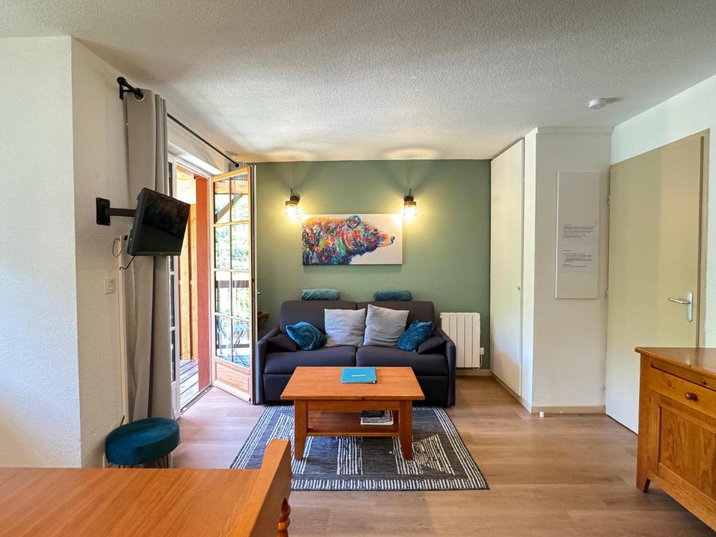een woonkamer met een bank en een tafel bij Joli duplex pr 5p, parking, balcon, piscine été in Cauterets