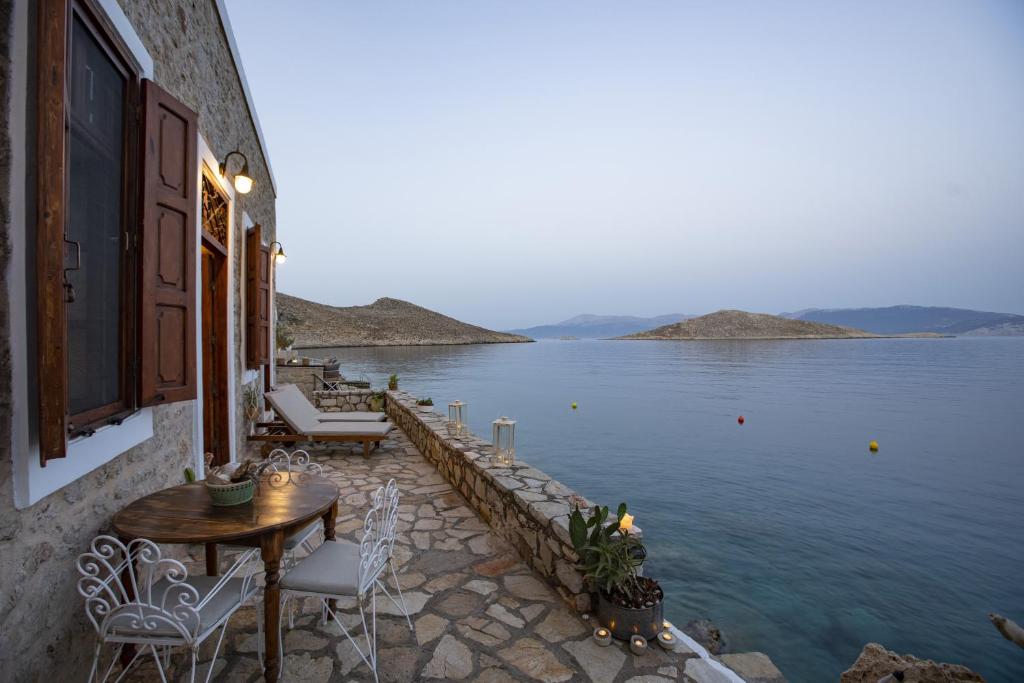 a patio with a table and chairs next to the water at Villa Electra in Halki