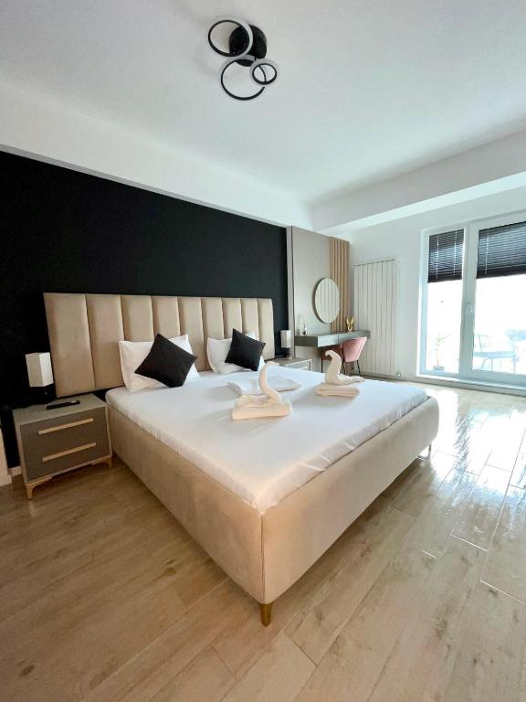 a bedroom with a large white bed with a black wall at Elite Summer Suite in Năvodari