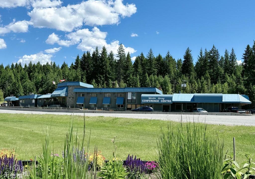 a large building with a grass field and trees at Wells Gray Inn in Clearwater