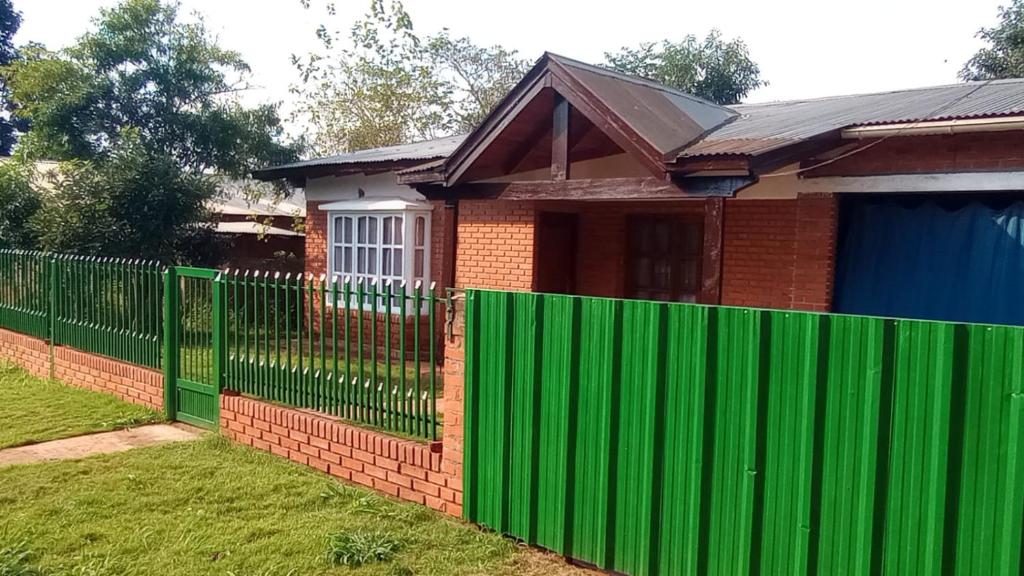 a green fence in front of a house at Amanecer Eldorado in Eldorado